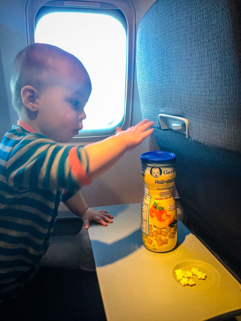 toddler on plane playing with puffs plane snacks for toddlers