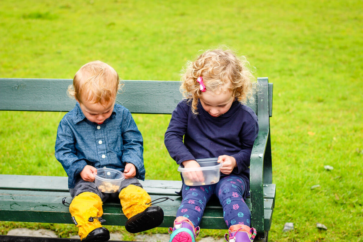 toddlers on bench holding snack cups for toddlers