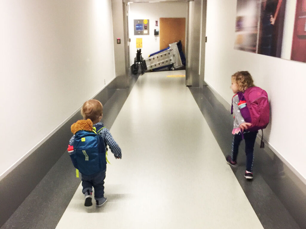 toddlers walking to airplane carrying toddler carry on backpacs