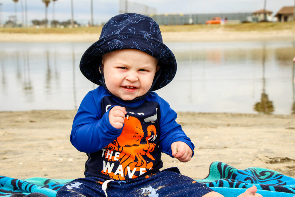 baby sitting on beach wearing one of the best baby boy sun hats