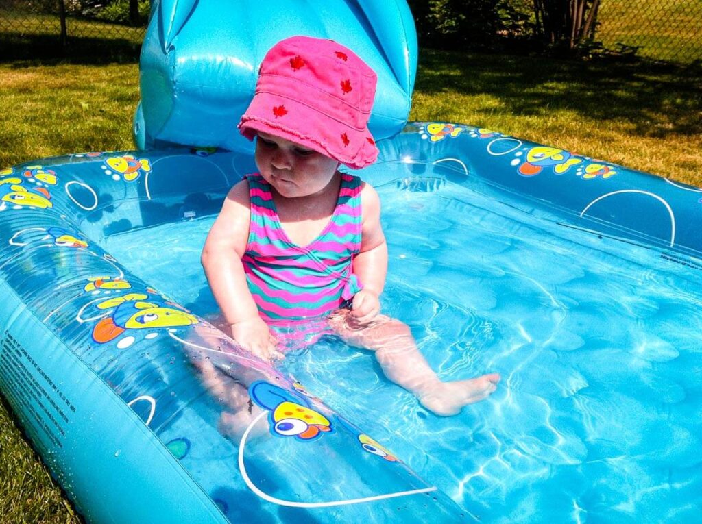 baby girl sitting in inflatable pool wearing best baby sun hat