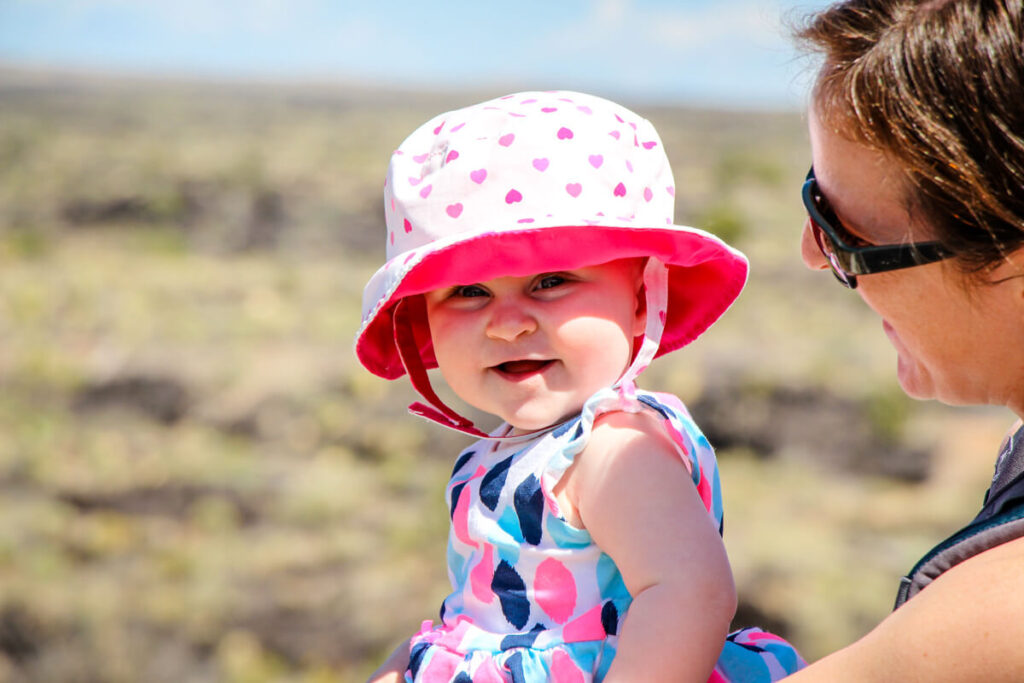 mother holding smiling baby who is wearing one of the best baby sun hats