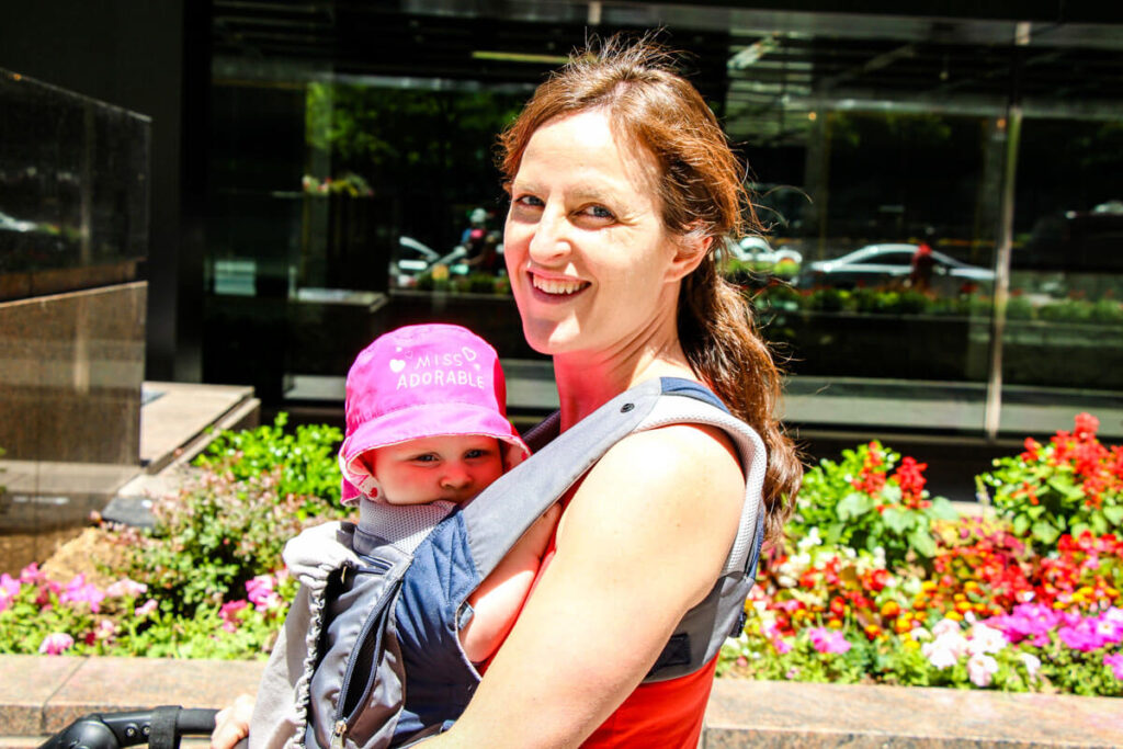 bother walking with baby in carrier wearing pink infant sun hat