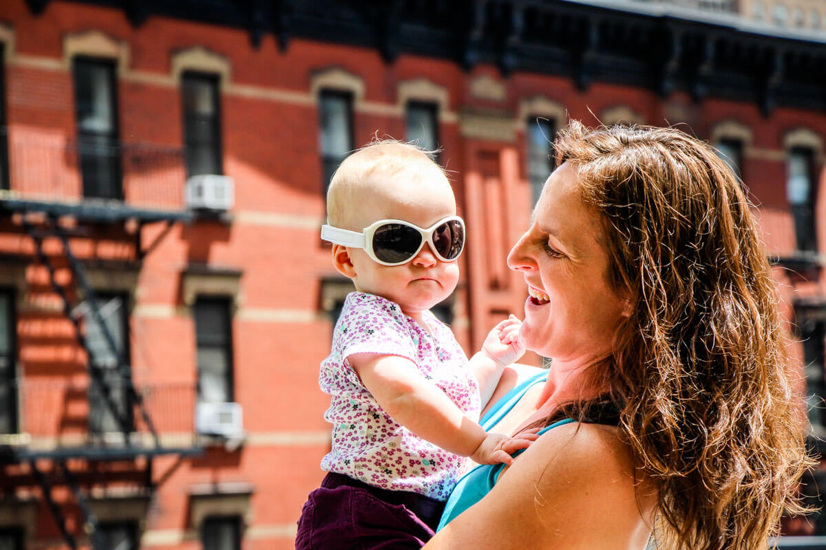 mother holding baby who is wearing baby girl sunglasses