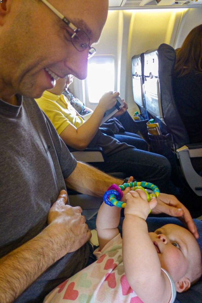 a happy baby plays with a simple toy during an international flight