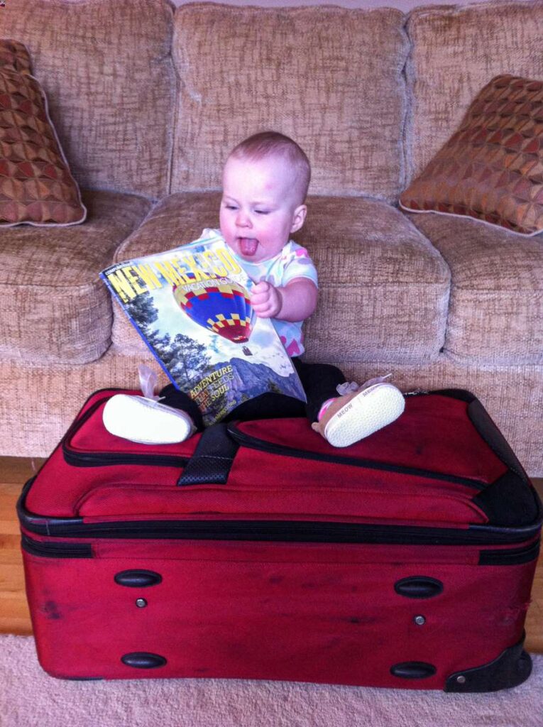 a cute baby site on a suitcase as her parents pack for traveling with a baby