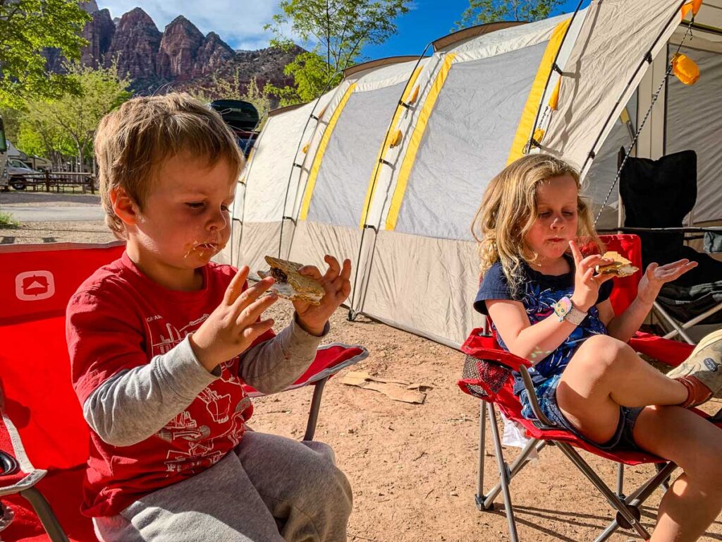 a toddler and his sister (from the Baby Can Travel family) enjoy s'mores while on a family camping trip to Zion National Park in Utah.