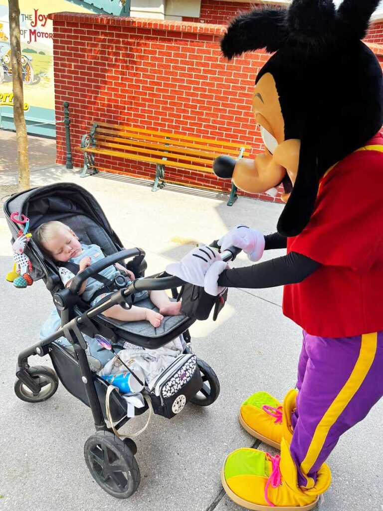 The Disney mascot Goofy pushes a stroller with a child at Disneyland Paris