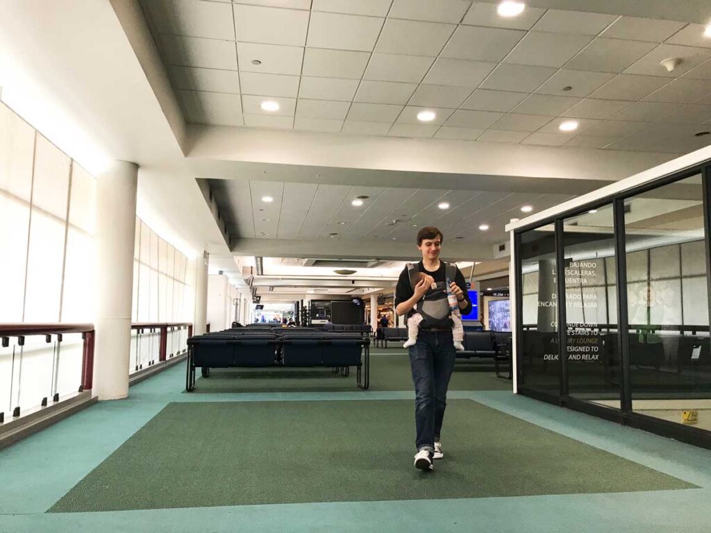 Father walking in Airport carrying baby in baby carrier