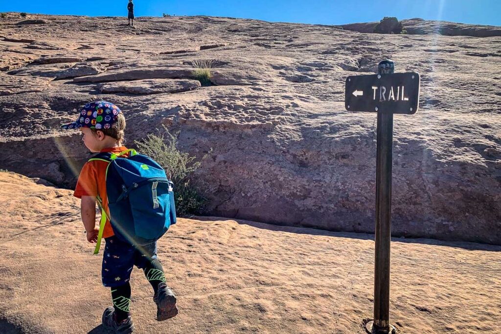 a toddler from the Baby Can Travel website wears a hiking backpack on a family camping trip to Utah.