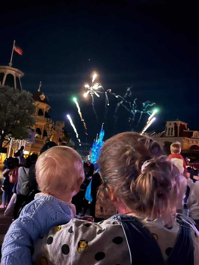 A mother watches evening fireworks at Disneyland Paris while on a family vacation to France