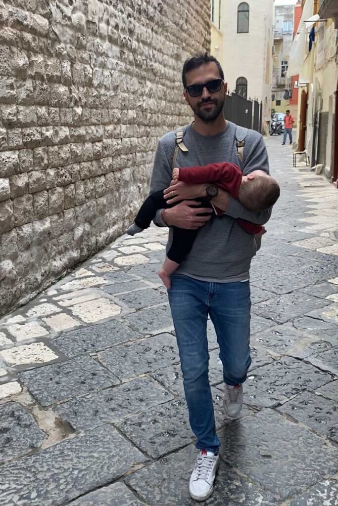 father holding sleeping baby on walking tour in Bari Italy