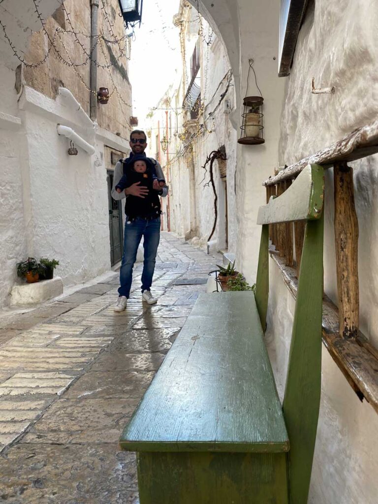 Father holding baby in baby carrier on vacation in Italy