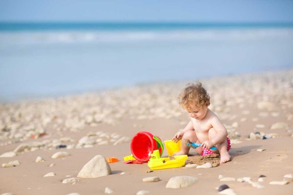 baby playing with beach toys - a must for taking a baby to the beach