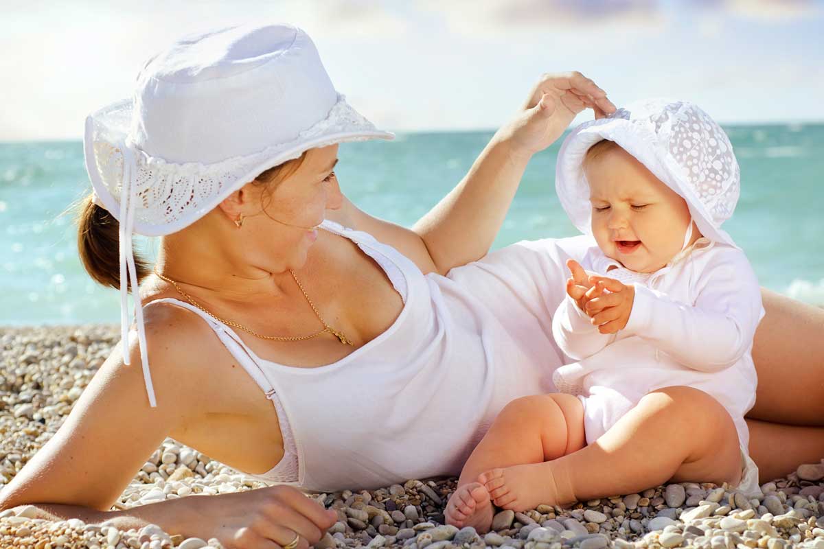 mother sitting with baby on beach