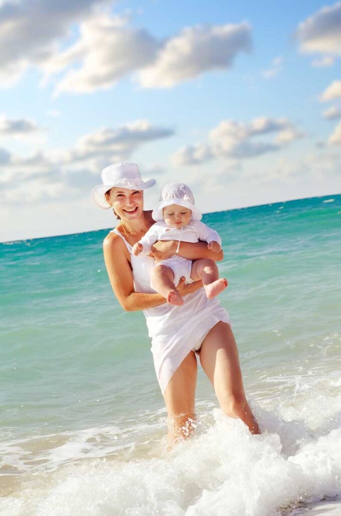 mother taking baby in water at the beach