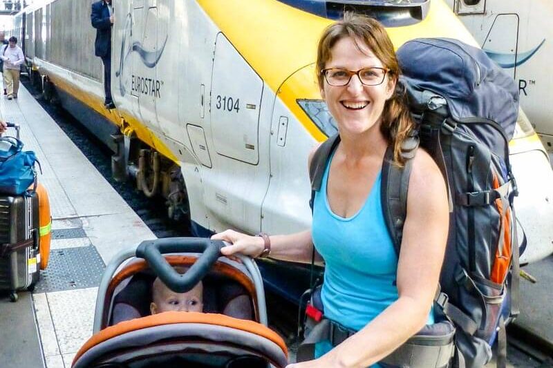 mother next to travel system with baby in car seat on stroller