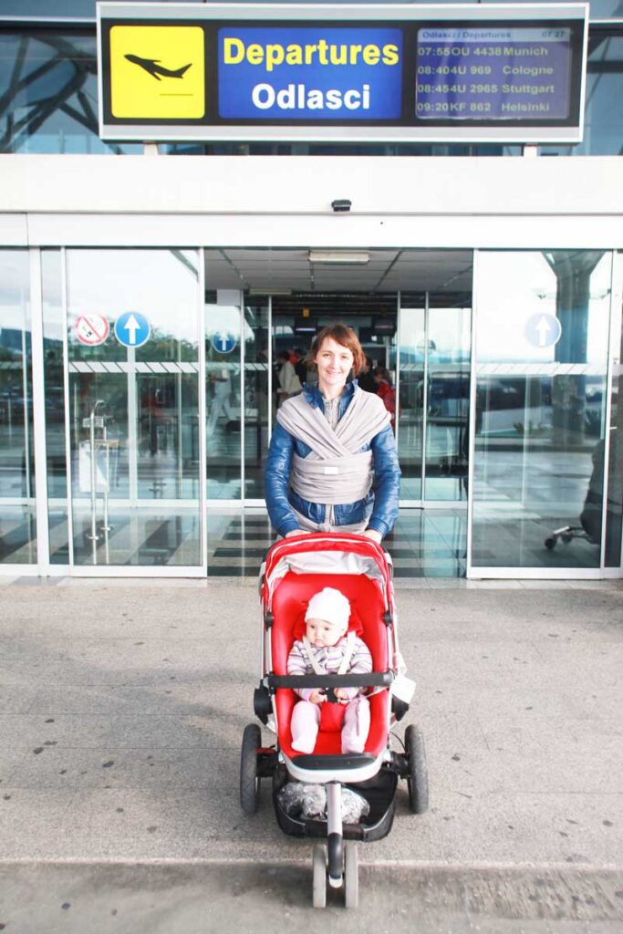 after flying with a stroller, a mother and baby leave the departures area of the airport. 