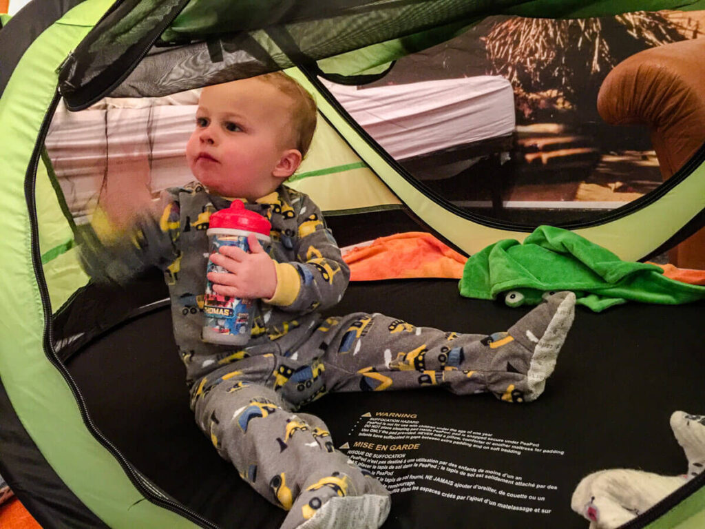 toddler in travel tent holding travel sippy cup