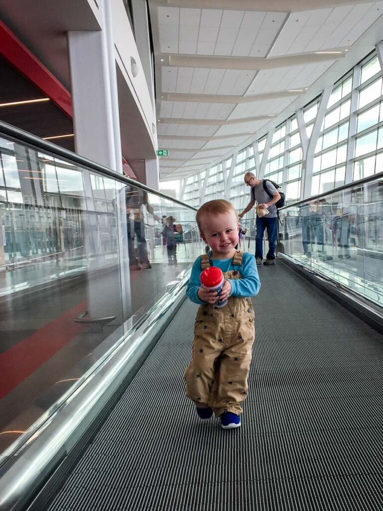 toddler walking in airport holding travel sippy cup