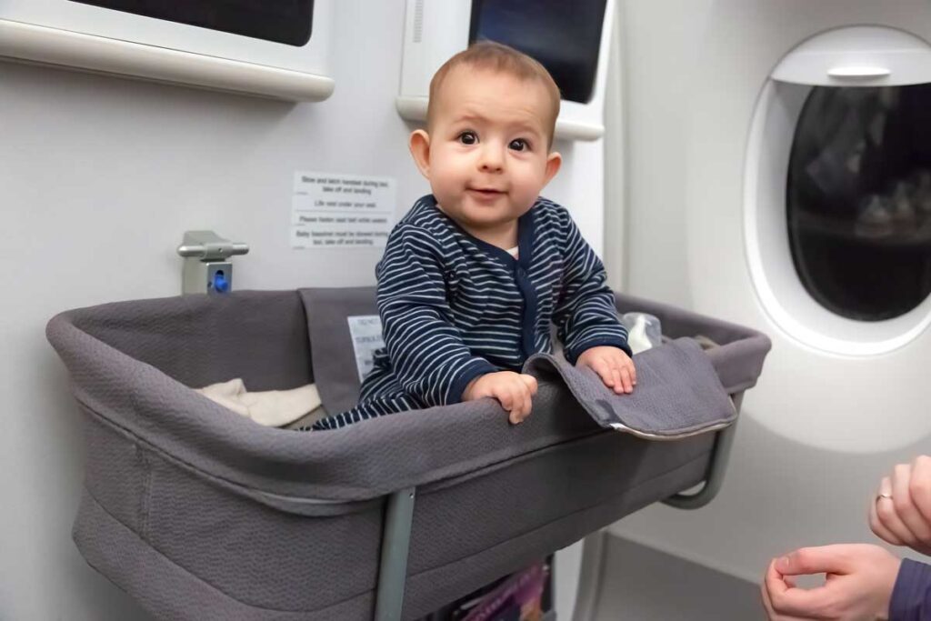 baby sitting up in bassinet on airplane.