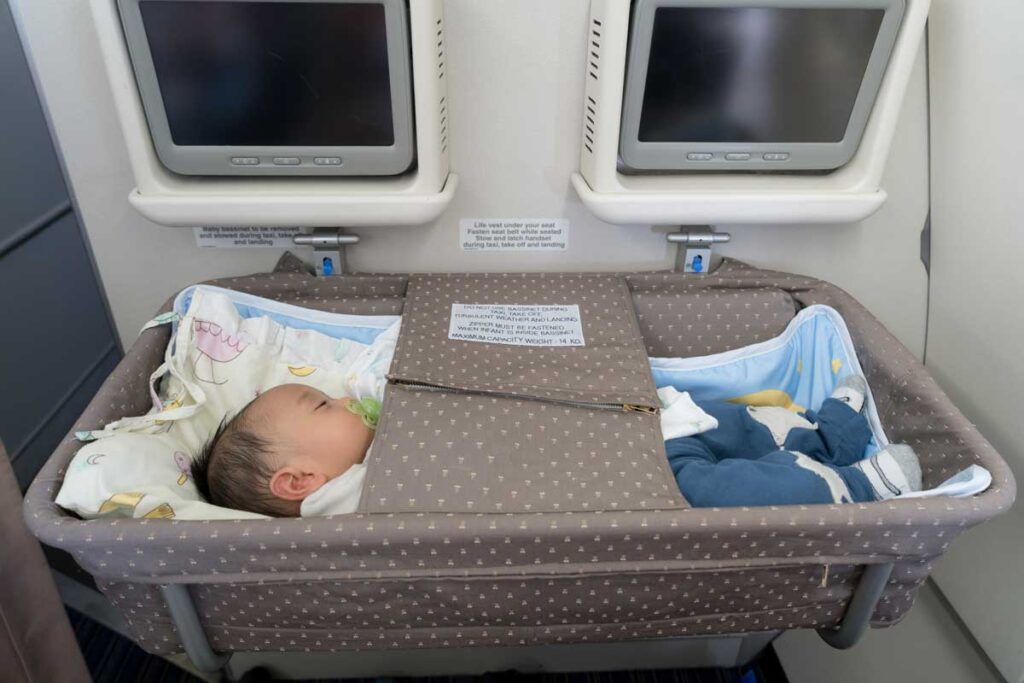 baby sleeping in bassinet on airplane.