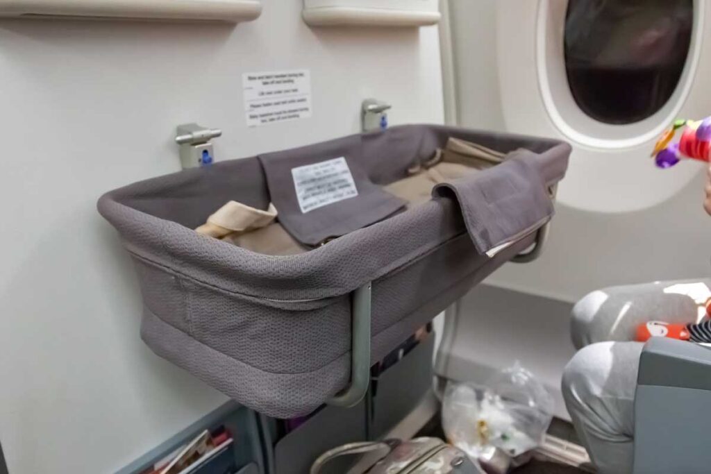 empty airplane bassinet attached to bulkhead in front of bulkhead seats.