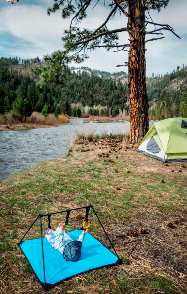 a baby plays with a travel play mat while camping.