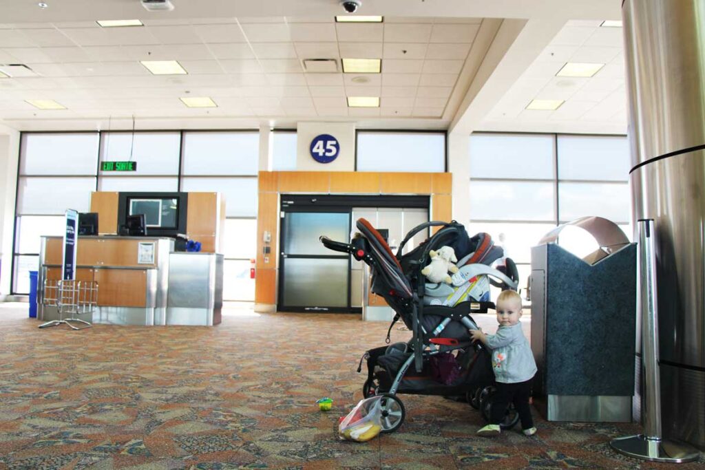 baby in front of stroller and car seat at the airport gate