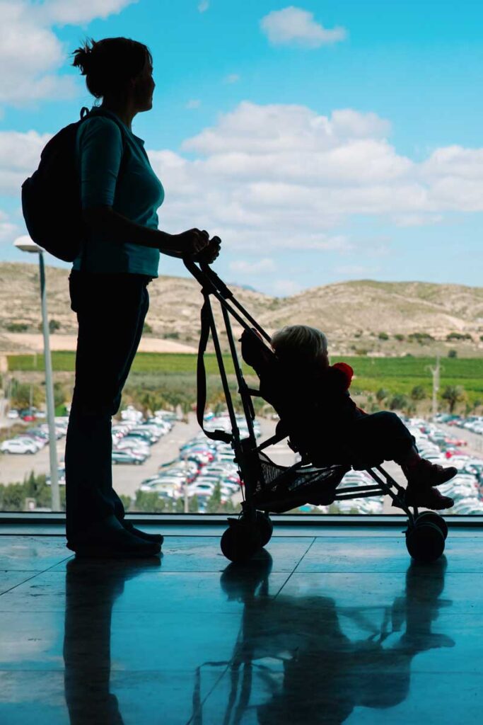 woman pushing a toddler in a stroller at airport