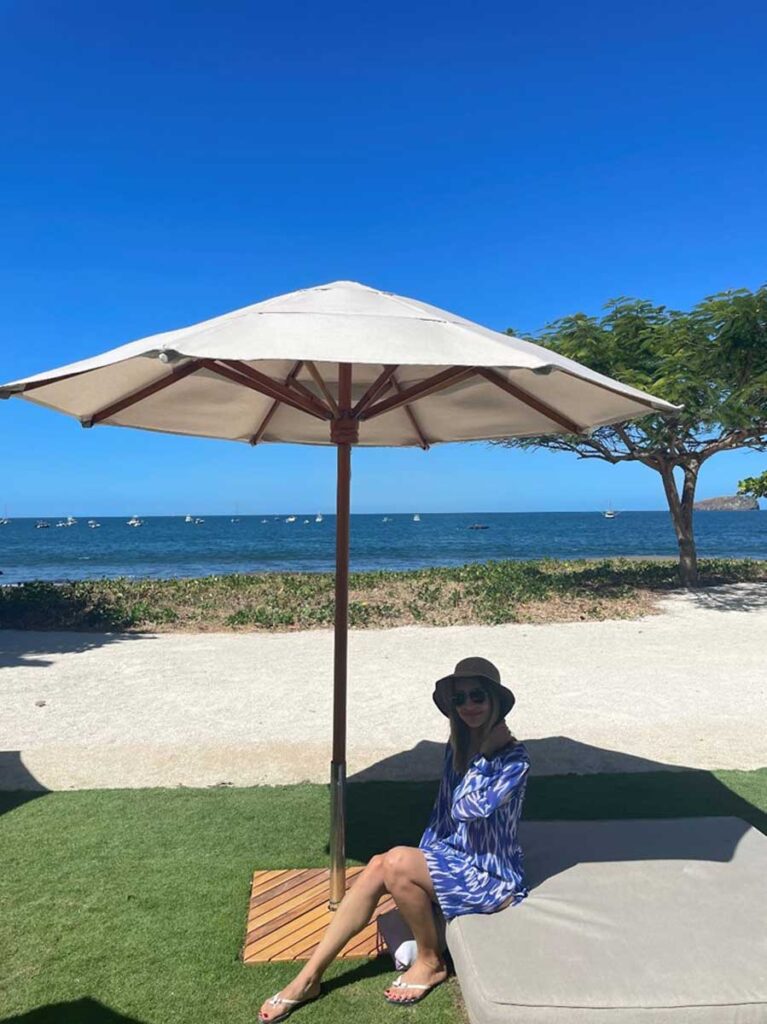 woman sitting under beach umbrella at Club Pacifico in Costa Rica