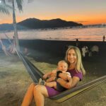 Woman holding baby on beach in Costa Rica at sunset