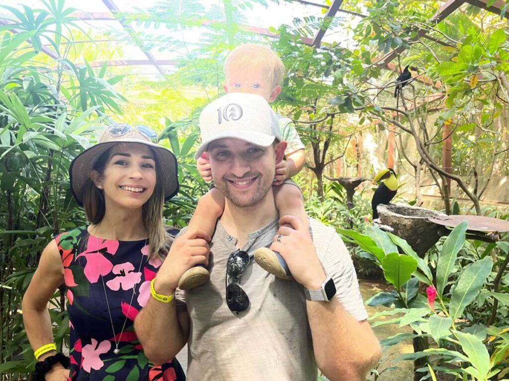 parents posing with baby on shoulders at Diamante Eco Adventure Park in Costa Rica with toddler