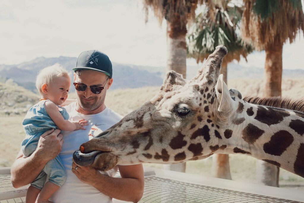 father holding baby near giraffe at Living Desert Zoo & Gardens - Palm Desert