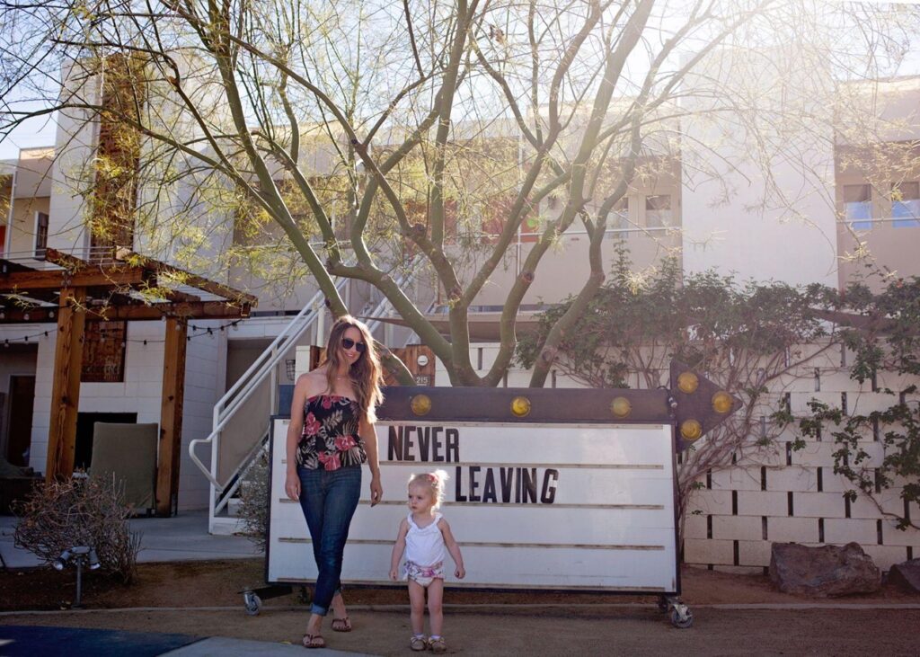 Mother and toddler in front of sign at The ACE hotel and swim club in Palm Springs