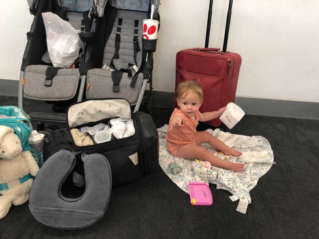 Using Zoe Twin Stroller at airport with baby sitting next to it on the floor