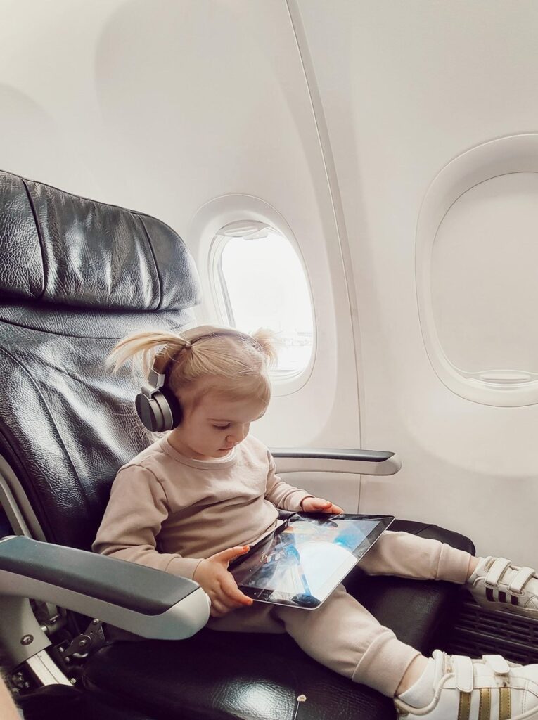 toddler wearing headphones watching ipad on airplane