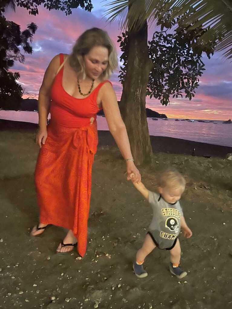 woman holding hands with walking toddler in Costa Rica on the beach