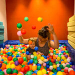 mother playing in ball pit with toddler