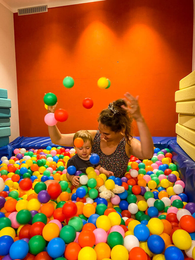 mother playing in ball pit with toddler on a family road trip through Germany.