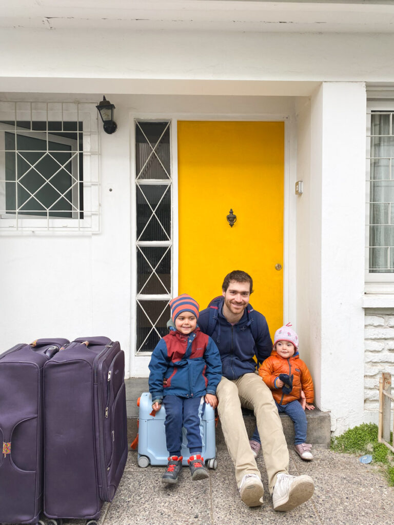 father and children sitting near front door with luggage and child on JetKids Bed Box