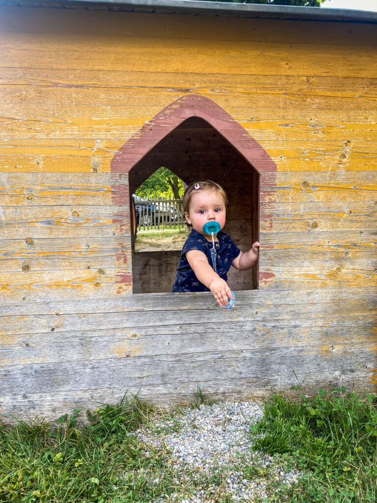 toddler in a wooden house in a playground on a family European road trip to Germany.