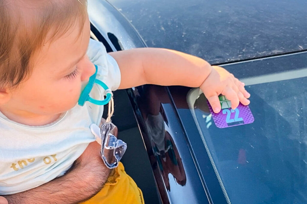 toddler playing with sticker on windshield on road trip in Europe.