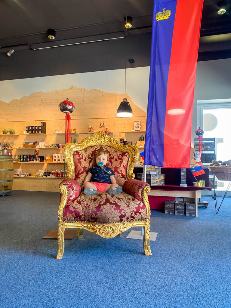 a baby sits on a throne in Vaduz, Liechtenstein. An example of the fun you can have on europe travel with toddler.