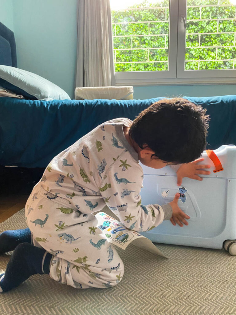 boy putting stickers on jetkids stokke bedbox ride-on suitcase