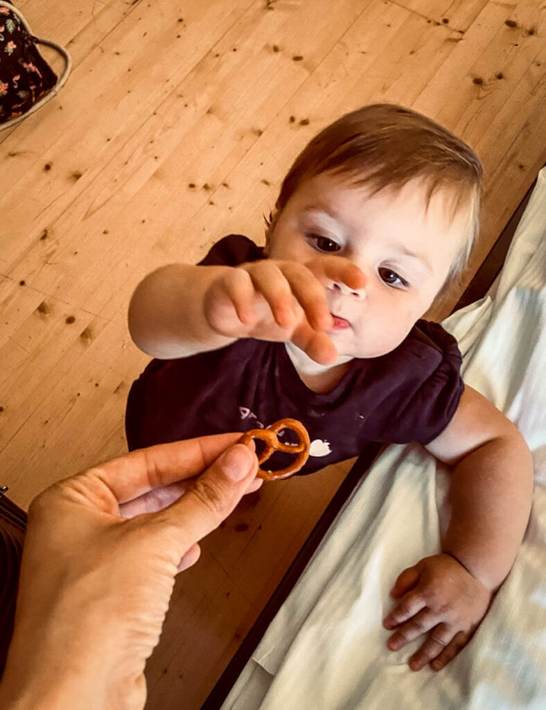 baby reaching for pretzel on a European road trip with her family.