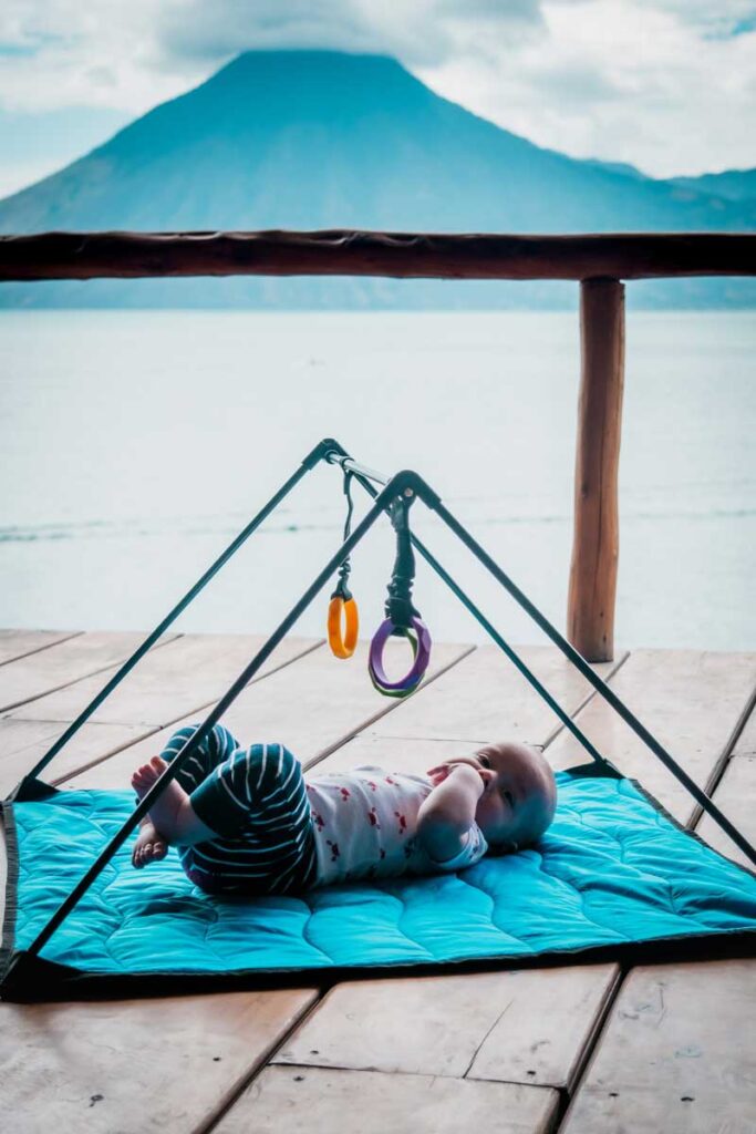 A to Z Adventure Gear Baby Travel Play Mat with baby on it with volcano in distance.