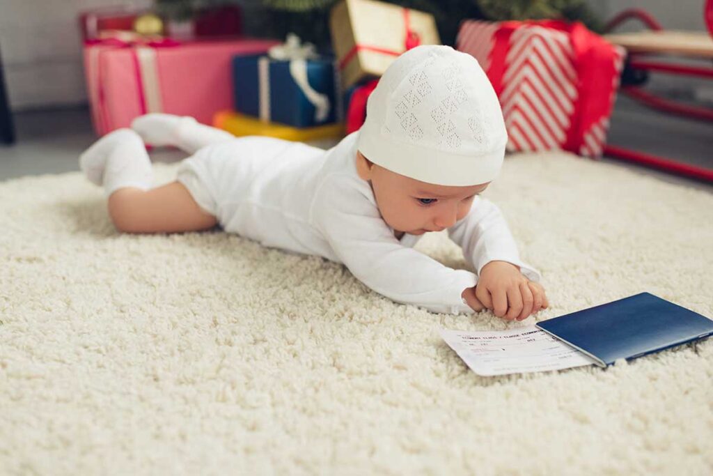 a baby reaches out to touch a passport and boarding pass.