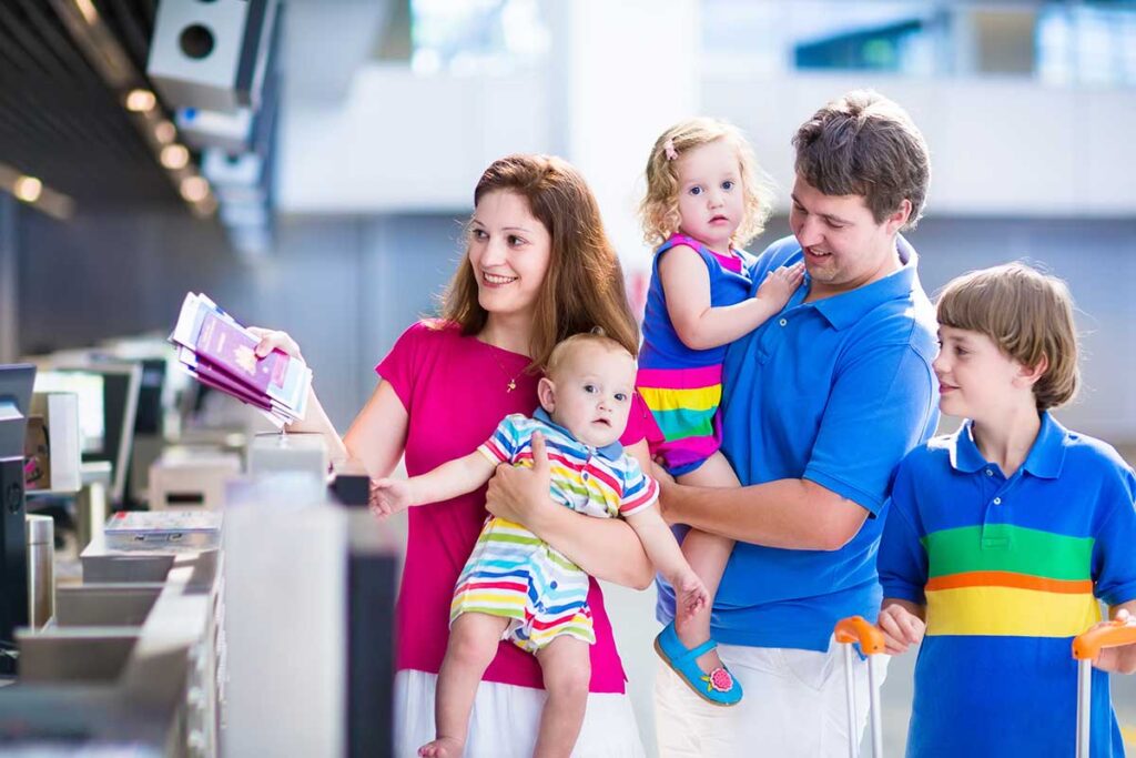 family at airport with mother holding baby and handing over passports