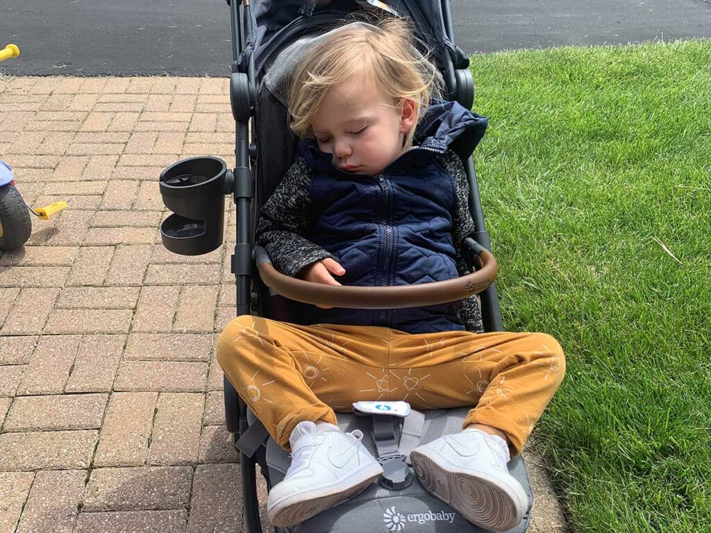 a toddler asleep in travel stroller.